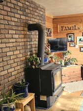 Living room featuring wooden walls, a textured ceiling, and a wood stove