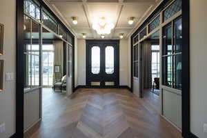 Entrance foyer with coffered ceiling, parquet floors, a notable chandelier, and french doors