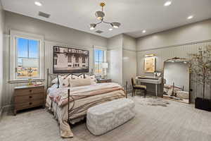 Bedroom featuring an inviting chandelier, light carpet, and multiple windows