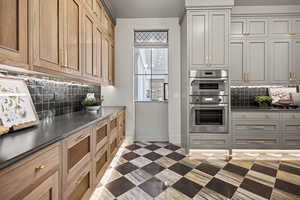 Kitchen with tasteful backsplash, stainless steel double oven, and gray cabinets