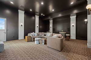 Carpeted cinema room featuring ornate columns