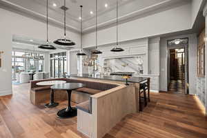 Kitchen with white cabinetry, a towering ceiling, wood-type flooring, and tasteful backsplash