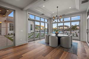 Dining area with crown molding, hardwood / wood-style floors, a towering ceiling, a notable chandelier, and a tray ceiling