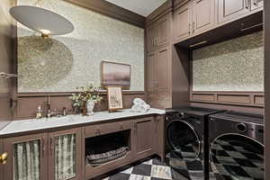 Clothes washing area with cabinets, independent washer and dryer, and sink