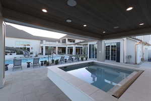 View of swimming pool with a water slide, a jacuzzi, and a patio