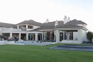 Rear view of house with a yard, a patio area, and a balcony