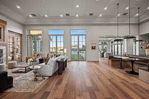 Living room with crown molding, light hardwood / wood-style floors, french doors, and a high ceiling