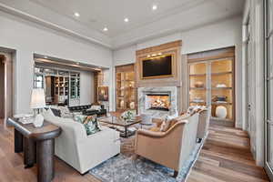 Living room with built in shelves, ornamental molding, hardwood / wood-style flooring, a fireplace, and a high ceiling