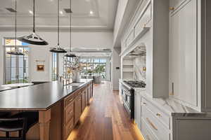 Kitchen featuring sink, double oven range, hanging light fixtures, and white cabinets