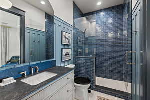 Bathroom with an enclosed shower, vanity, tile patterned flooring, and toilet