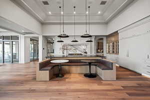 Kitchen with a kitchen breakfast bar, ornamental molding, white cabinets, decorative light fixtures, and light wood-type flooring