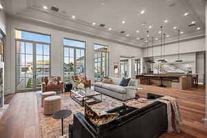 Living room with french doors, a towering ceiling, ornamental molding, and hardwood / wood-style floors