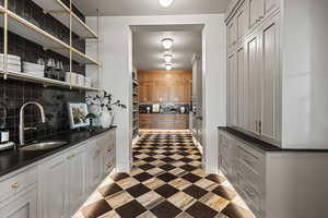 Bar with sink, backsplash, and gray cabinets