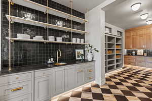 Bar featuring sink, white cabinets, and decorative backsplash