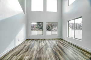 Unfurnished living room with hardwood / wood-style flooring, plenty of natural light, and a high ceiling