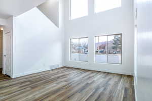 Unfurnished living room featuring hardwood / wood-style flooring and a towering ceiling