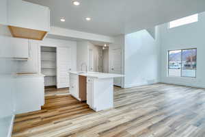 Kitchen featuring white cabinetry, sink, a center island with sink, and light hardwood / wood-style floors