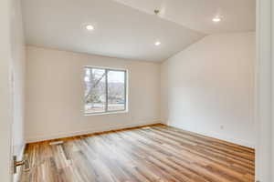 Unfurnished room featuring vaulted ceiling and light hardwood / wood-style floors