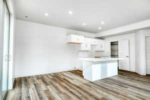 Kitchen with a kitchen island with sink, sink, light hardwood / wood-style flooring, and white cabinets