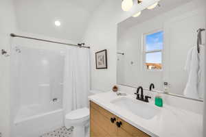 Full bathroom featuring vanity, shower / bathtub combination with curtain, and toilet