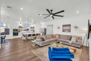 Living room with ceiling fan, sink, and light wood-type flooring