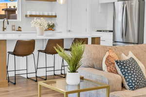 Interior space with white cabinetry, sink, stainless steel fridge, and light hardwood / wood-style floors