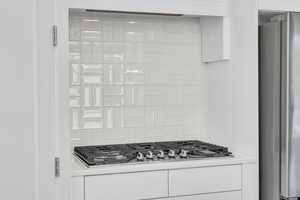 Details with white cabinetry, appliances with stainless steel finishes, and backsplash