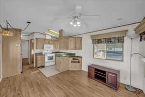 Kitchen with vaulted ceiling, hanging light fixtures, white appliances, light brown cabinets, and light wood-type flooring