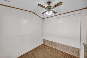 Spare room with ornamental molding, lofted ceiling, ceiling fan, and light hardwood / wood-style floors