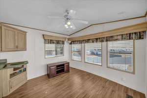 Kitchen featuring lofted ceiling, hardwood / wood-style flooring, ceiling fan, crown molding, and light brown cabinets