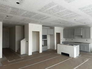 Kitchen with gray cabinetry, wall chimney range hood, and a kitchen island