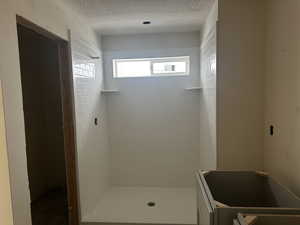 Bathroom with tiled shower and a textured ceiling