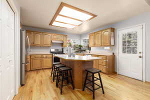 Kitchen with appliances with stainless steel finishes, a breakfast bar, a kitchen island, and light wood-type flooring