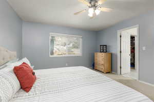 Carpeted bedroom featuring a spacious closet and ceiling fan