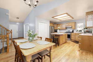 Dining room with light wood-type flooring, lofted ceiling, sink, and a notable chandelier