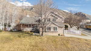 View of property featuring a porch, a mountain view, and a front yard