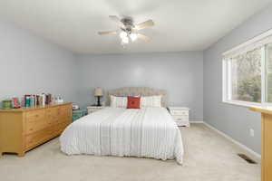 Carpeted bedroom featuring ceiling fan