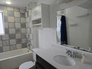 Full bathroom featuring vanity, shower / bath combination with curtain, a textured ceiling, and toilet