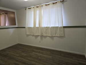 Unfurnished room featuring dark wood-type flooring and a textured ceiling