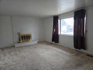 Unfurnished living room with a fireplace, carpet floors, and a textured ceiling