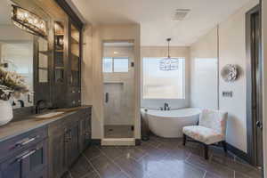 Bathroom featuring vanity, separate shower and tub, and a chandelier