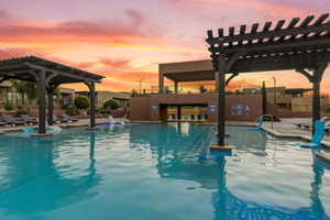 Pool at dusk with a pergola and a patio area