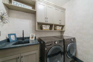 Laundry room featuring independent washer and dryer, cabinets, and sink