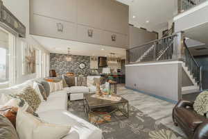 Living room featuring a notable chandelier, light hardwood / wood-style floors, and a high ceiling