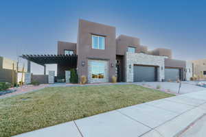 Pueblo-style home featuring a garage and a front yard