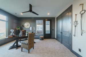 Office area with ceiling fan and light colored carpet