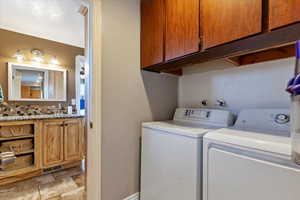 Washroom with washing machine and clothes dryer and sink