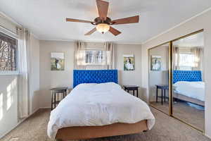 Bedroom featuring ceiling fan, light colored carpet, a textured ceiling, and a closet