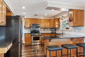 Kitchen featuring sink, a breakfast bar area, stainless steel appliances, dark hardwood / wood-style flooring, and kitchen peninsula