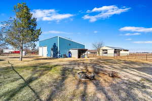 View of outbuilding featuring an outdoor fire pit, a lawn, and a rural view